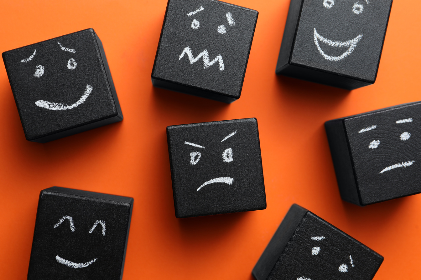 Many cubes with different emotions on orange background, flat lay. Emotional management